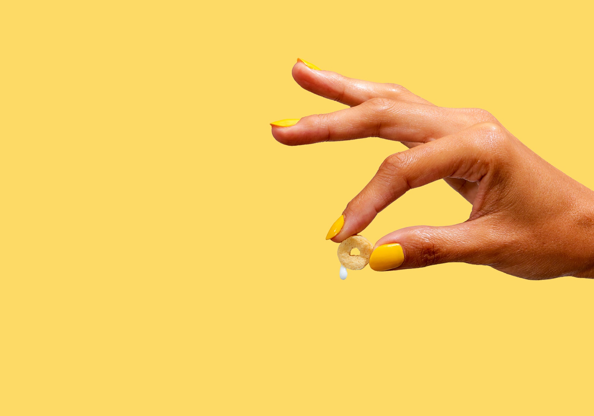 human hand holding cereal on yellow background